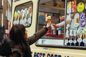 A woman receiving an ice cream cone from a truck.