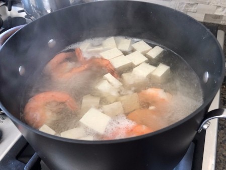Simmering tofu and shrimp in a stockpot.