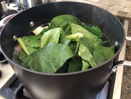 Adding chopped bok choy to the stockpot.