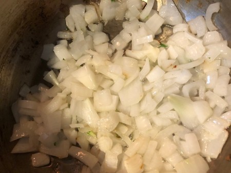 Onions being sauteed in a soup pan.