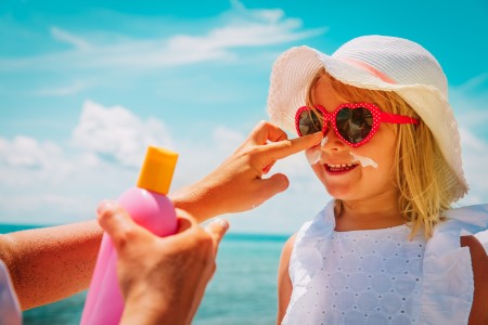 A mother putting sunscreen on a young girl.