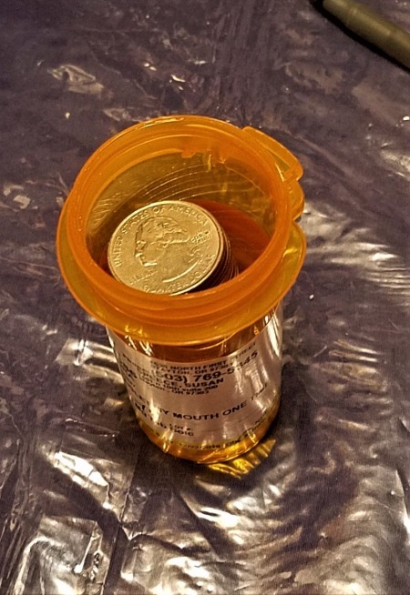 Quarters stored in an old prescription bottle.