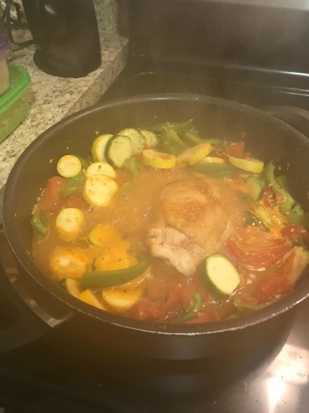 Cooking chicken and vegetables in a frying pan.
