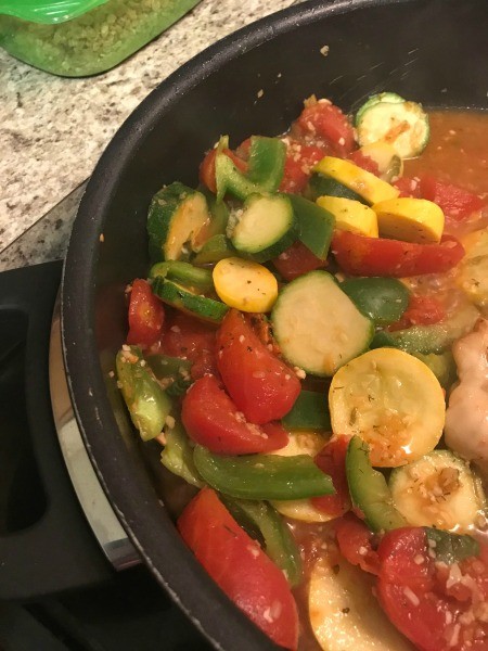 Cooking chicken and vegetables in a frying pan.