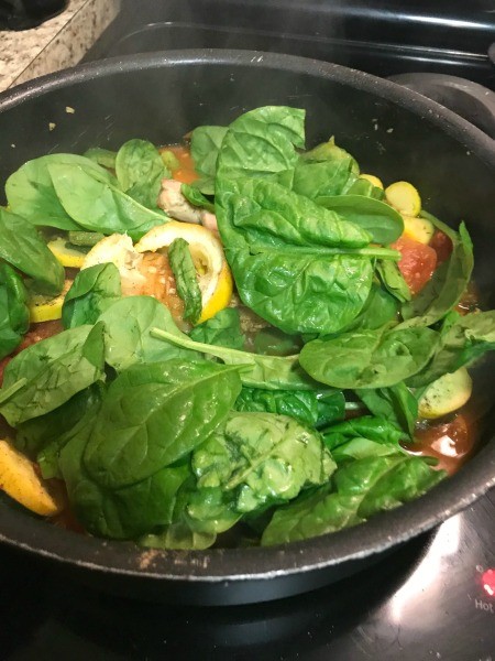 Cooking chicken and vegetables in a frying pan.