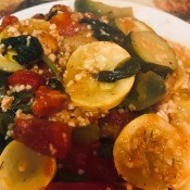 A plate of chicken and vegetables over rice pilaf.