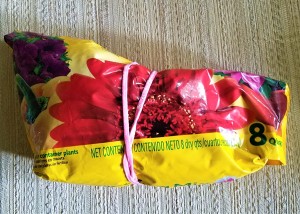 A headband being used as a rubber band around an open bag of potting mix.