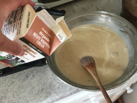 Adding heavy cream to the ice cream mixture.
