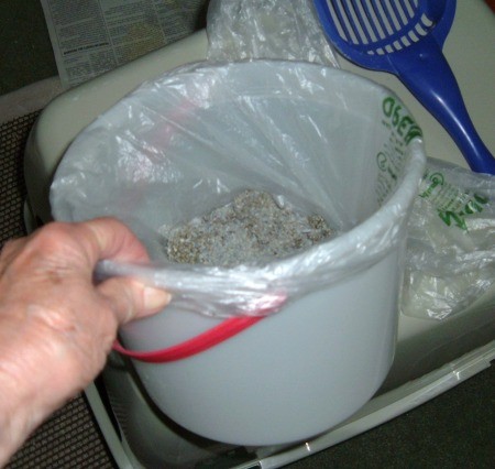 A plastic bag in a bucket with cat litter.