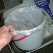A plastic bag in a bucket with cat litter.