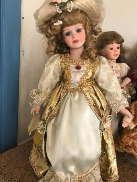 A fancy porcelain doll in a gold and white dress.