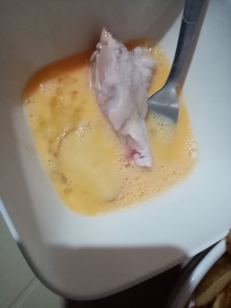 Dipping chicken in an egg mixture.