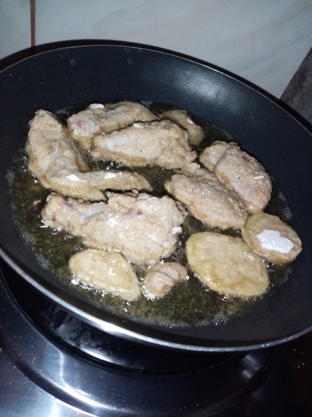 Frying the dredged chicken in a pan with oil.