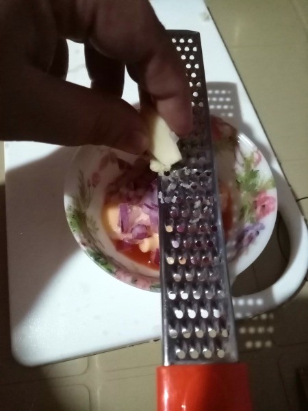 Grating garlic into a dish.