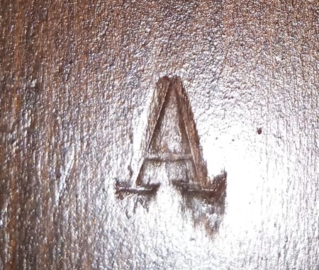 A letter A stamped or carved into the wood of a table.