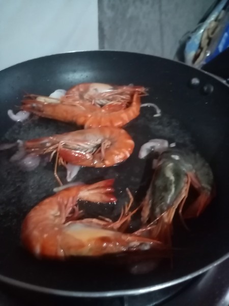 A frying pan with cooked shrimp.