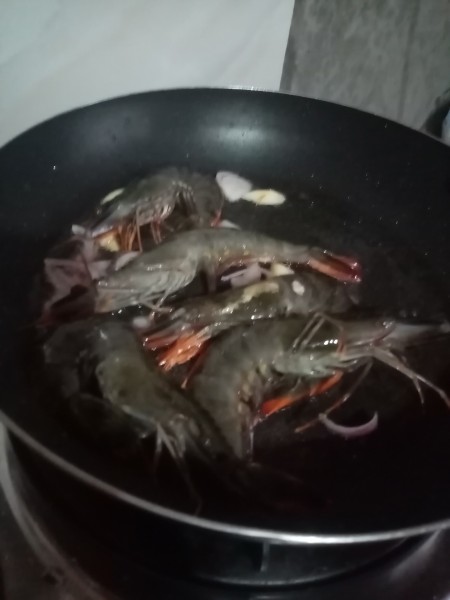A frying pan with uncooked shrimp.