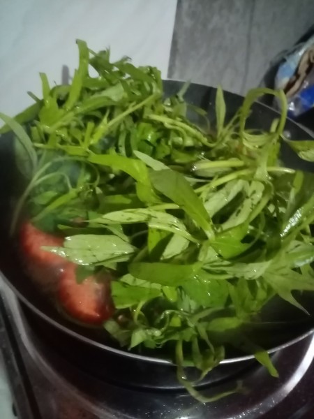 Adding greens to the soup mixture.