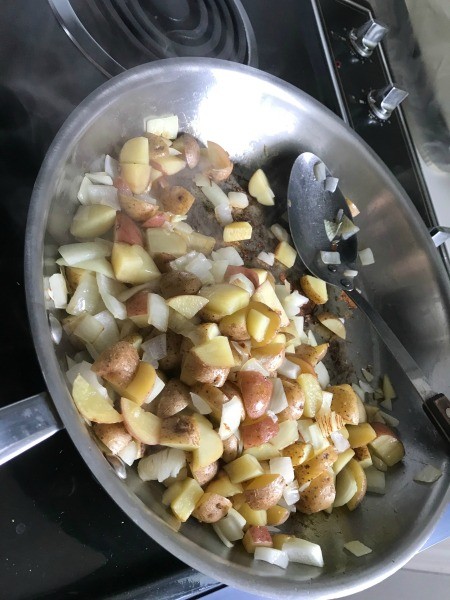 Cooking the potatoes and onions in a frying pan.