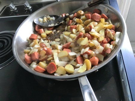 Adding the hot dogs to the pan.