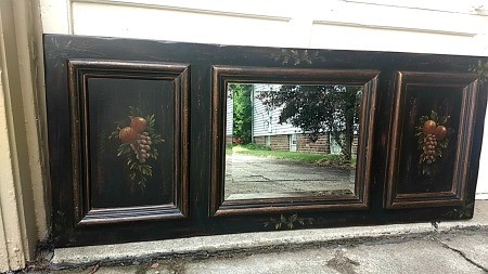 A three part panel with mirror in center and fruit painted on the other two