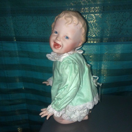 A kneeling porcelain doll in green.