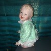 A kneeling porcelain doll in green.