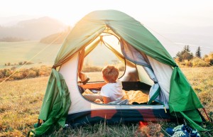 A small boy in a tent overlooking a valley.