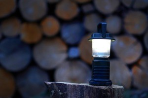 A lantern in front of a stack of wood.