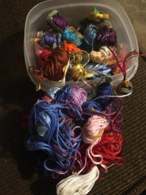 Several skeins of embroidery floss in a plastic container.