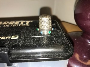A silver thimble with overall pattern and blue stones set in the rim