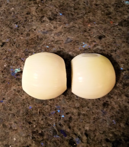 Splitting the onion in half and removing the outer skin.