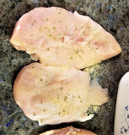 Two chicken breasts that have been seasoned.