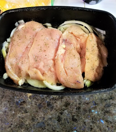 The chicken breasts are placed on top of the sliced onions.