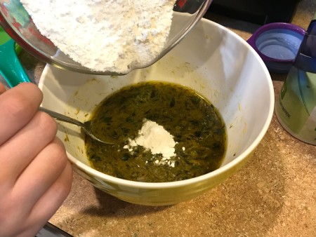 Dandelion Playdough -adding flower to a bowl with the liquid