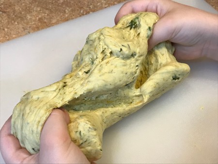 Dandelion Playdough - child's hands stretching the dough