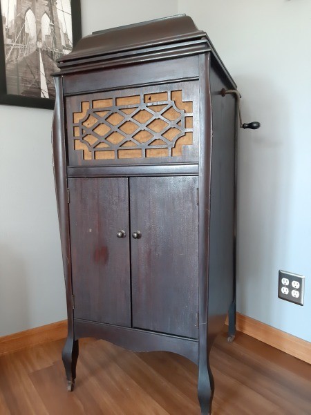 A dark wood antique record player with a hand crank