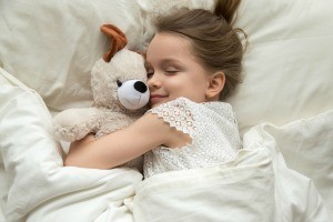 A little girl in bed with her stuffed animal.