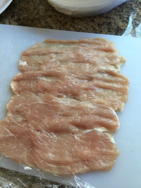 Pork that has been pounded flat on a cutting board.