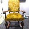 An antique chair covered in yellow cloth.