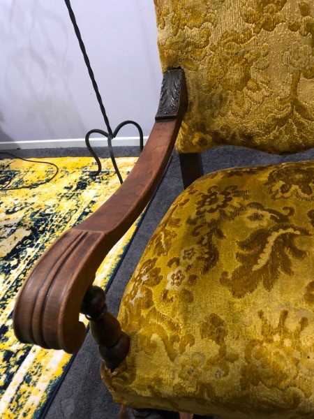 The arm and seat of an antique chair.