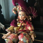 A porcelain doll in a colorful costume with a jester's hat.