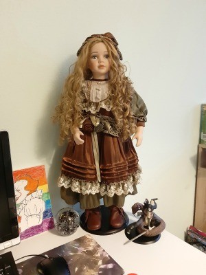 A blonde porcelain doll with old fashioned clothing.