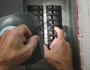 A person looking at a circuit breaker with a flashlight.