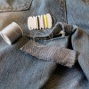 A pair of jeans being mended with needle and thread.
