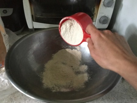 Adding flour to a mixing bowl.