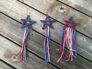 4th of July Craft Stick Star with Streamers - three of the star decorations lying on a deck