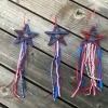 4th of July Craft Stick Star with Streamers - three of the star decorations lying on a deck