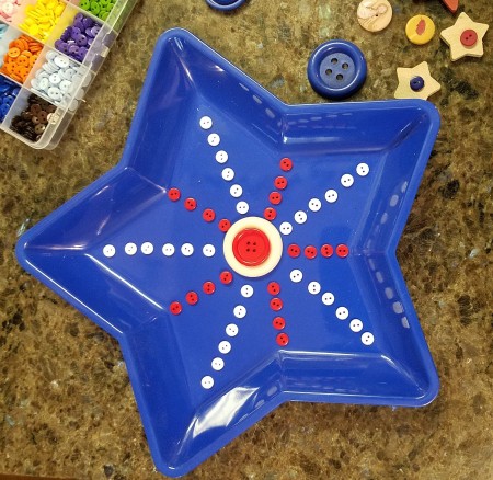 Blue Star Wall Hanging - mini white buttons glued out towards the star points and red ones to the valleys between, white button with a smaller red one attached in the center of the star