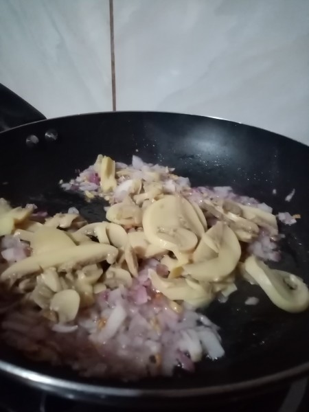 Adding mushrooms to the pan.